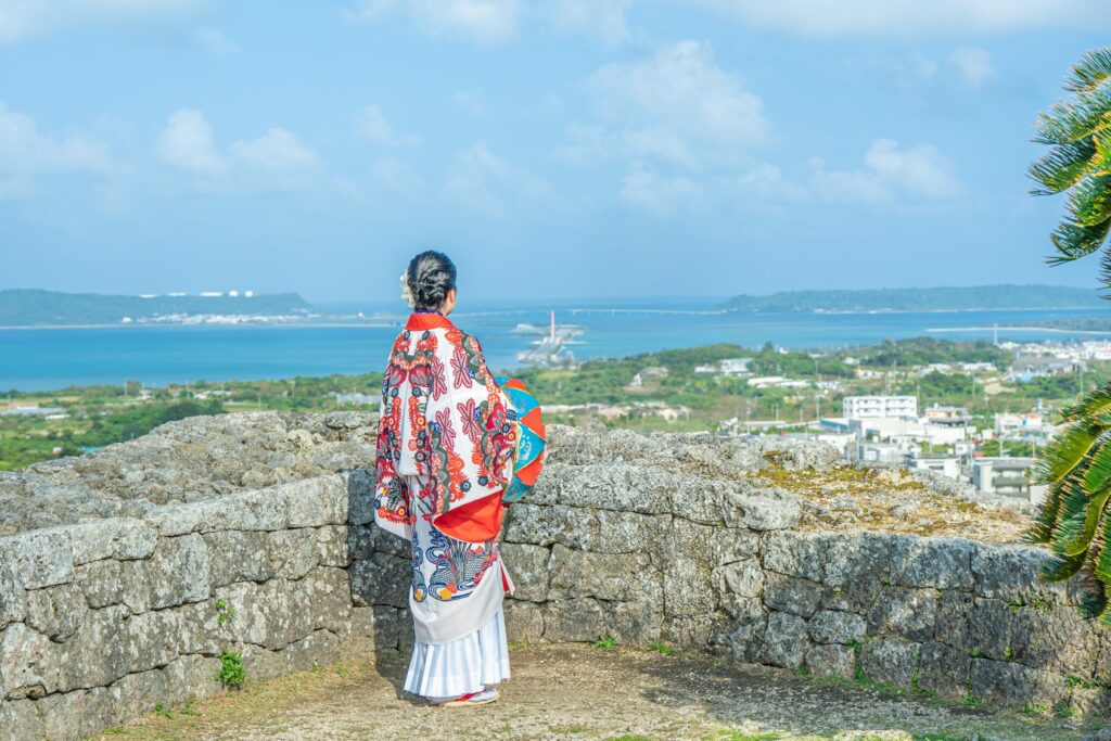 沖縄の海を背景に和服を着た女性が振り返っている風景